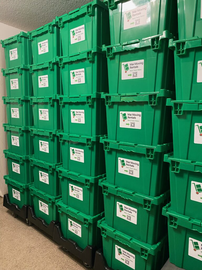 Rows of green reusable moving boxes from “Mai Moving Rentals” stacked on black dollies in Toronto