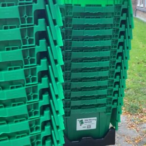 Stacks of green reusable moving boxes from “Mai Moving Rentals” on a dolly outside a Toronto building