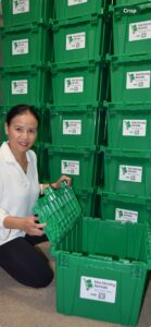 Mai Moving Rentals owner beside stacked green reusable moving boxes labeled “Mai Moving Rentals,” opening one container in Toronto GTA